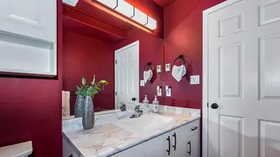 a red bathroom with a sink and a vase of flowers at Knockan Hill Rentals - Ground Floor Suite in Victoria