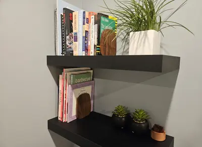 a black book shelf with books and potted plants at Cowichan Valley Retreat with Sauna & Free EV Charger in Duncan