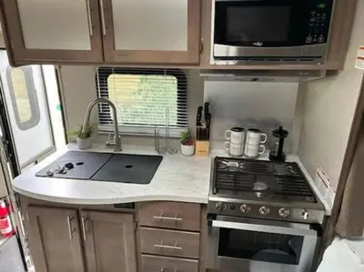 a small kitchen with a stove and a microwave at Prairie Junction Resort - Furnished RV Apartments in Stettler