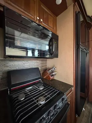 a kitchen with a stove and a microwave at Prairie Junction Resort - Furnished RV Apartments in Stettler