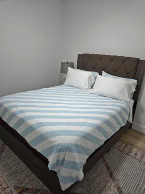 a bed with a blue and white striped blanket at Spacious 2 Bedroom Suite in Edmonton in Edmonton