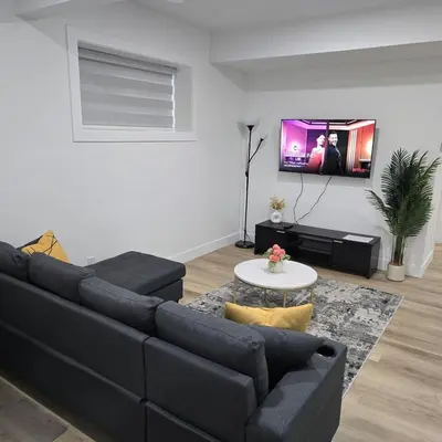 a living room with a couch and a tv on a wall at Spacious 2 Bedroom Suite in Edmonton in Edmonton