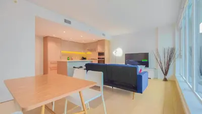 a living room with a table and a blue couch at Modern High-Rise Condo with Stunning Garden Views in Richmond