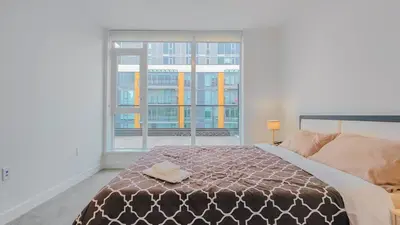 a bedroom with a bed and a large window at Modern High-Rise Condo with Stunning Garden Views in Richmond