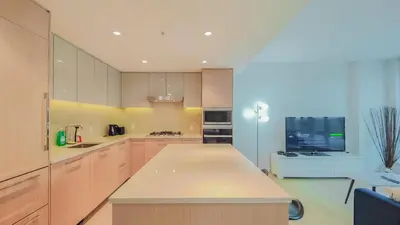 a kitchen with wooden cabinets and a tv in it at Modern High-Rise Condo with Stunning Garden Views in Richmond