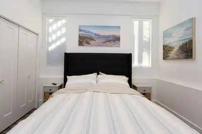 a white bedroom with a large bed with two windows at Sidney Solace 1BR Suite Minutes from Waterfront in Sidney