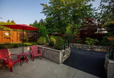 a patio with two red chairs and an umbrella at Sidney Solace 1BR Suite Minutes from Waterfront in Sidney