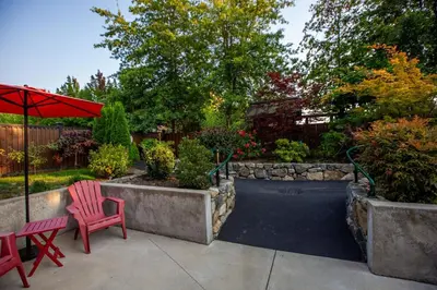 a patio with two red chairs and an umbrella at Sidney Solace 1BR Suite Minutes from Waterfront in Sidney