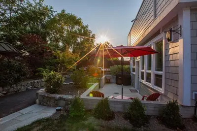 a house with a patio with a red umbrella at Sidney Solace 1BR Suite Minutes from Waterfront in Sidney