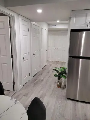 a kitchen with white cabinets and a stainless steel refrigerator at Coastal Comforts Villa in Airdrie