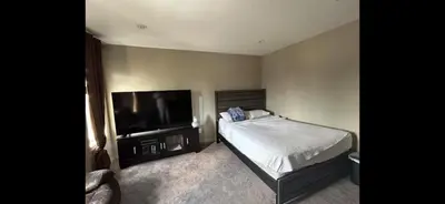 a bedroom with a bed and a flat screen tv at Coastal Comforts Villa in Airdrie