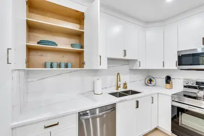 a white kitchen with white cabinets and a sink at The Olaf in Trendy Killarney - Close to Everything in Calgary
