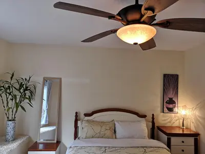 a ceiling fan in a bedroom with a bed at Abbie's Cozy Single Rooms in Maple Ridge District Municipality