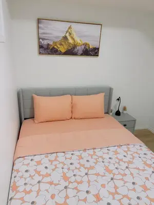 a bed with orange pillows and a picture on the wall at Chezeey Home in Edmonton