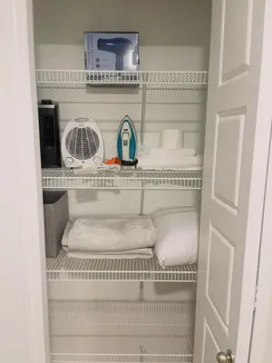 a closet with white shelves and a fan and towels at Chezeey Home in Edmonton