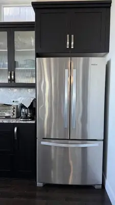 a stainless steel refrigerator in a kitchen with black cabinets at Carrie's The Gentle Nest No 2 in Coquitlam