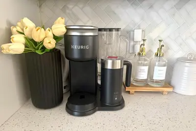 a coffee maker on a counter with a vase of flowers at Entire Home - backyard oasis, indoor fireplace, Huge TV in Fort McMurray
