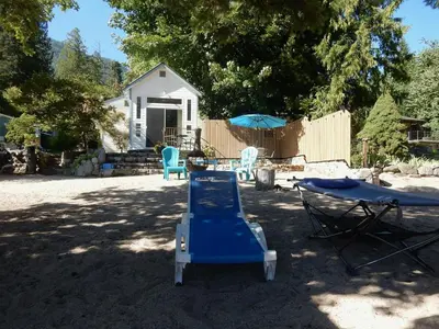 a blue lawn chair and a table and an umbrella at Beach front cabin near Nelson, BC in Nelson