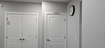 two white doors in a hallway with a clock on the wall at Glacier Comfort Living Suite in Calgary