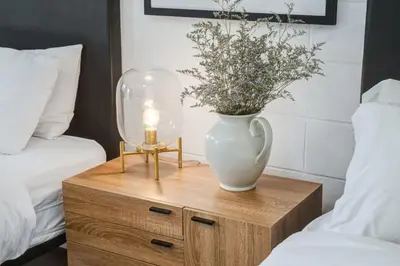 a vase on a wooden nightstand with a lamp and a table with at Gateway Suites Single Private Room Near Banff and Canmore in Canmore