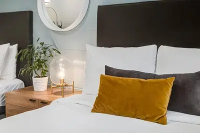 a bedroom with a bed with white sheets and yellow pillows at Gateway Suites Private Double room Near Canmore and Banff in Canmore