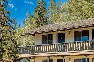 a house with a large deck in the woods at Gateway Suites Private Double room Near Canmore and Banff in Canmore