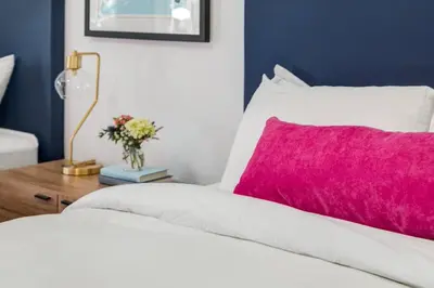 a white bed with a pink pillow and a table at Gateway Suites Private Double room near Banff in Canmore