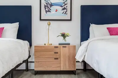 a bedroom with two beds and a night stand with flowers at Gateway Suites Private Double room near Banff in Canmore