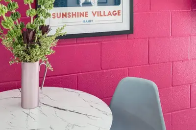 a table with a vase of flowers on a pink wall at Gateway Suites Private Double room near Banff in Canmore