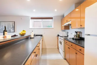 a kitchen with wooden cabinets and a black counter top at Adorable, 2 Bedrooms in West Vancouver in West Vancouver