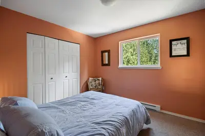 a bedroom with orange walls and a bed and a window at Pet friendly Family home in Shawnigan Lake in Shawnigan Lake