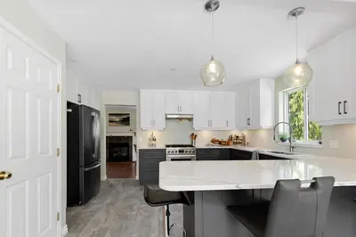 a kitchen with white cabinets and a black refrigerator at Pet friendly Family home in Shawnigan Lake in Shawnigan Lake
