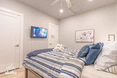 a bedroom with a bed with a tv on the wall at Skaha Suites in Penticton