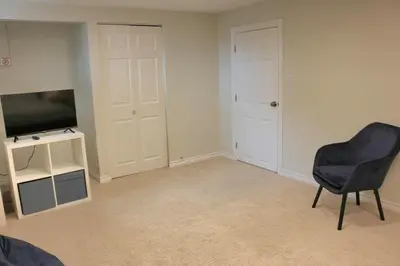 an empty living room with a television and a chair at Home beside WEM in Edmonton