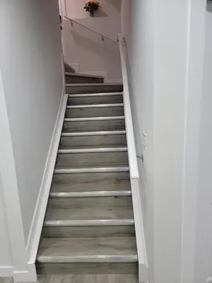 a staircase with white walls and wooden floors at Cozy Suite near West Edmonton Mall in Edmonton