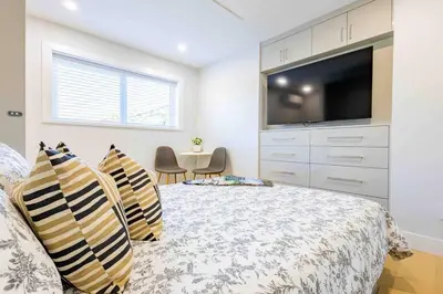 a bedroom with a bed with a tv on the wall at Charming & Brand-New near Restaurants & Transport in Vancouver