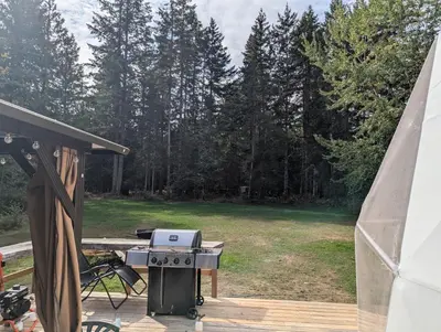 a grill on a deck next to a yard at Bela bahia in Qualicum Beach