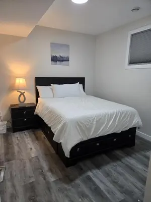 a bedroom with a large bed with a white bedspread at Cozy Basement Suite, SW Calgary in Calgary