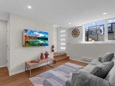 a living room with a couch and a clock on the wall at Superb 1-Bdr Apt in New Condo in Calgary