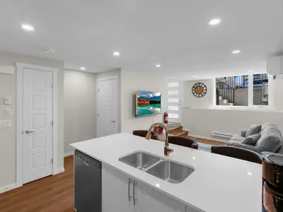 a kitchen with a sink and a living room at Superb 1-Bdr Apt in New Condo in Calgary