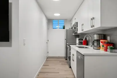 a kitchen with white cabinets and a white door at Private Basement Magnolia Retreat Family Friendly Suite near Seton and Lake in Calgary