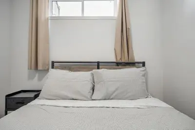 a bed in a room with a window and a bed with pillows at Private Basement Magnolia Retreat Family Friendly Suite near Seton and Lake in Calgary