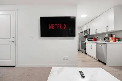 a kitchen with a television on a white wall at Private Basement Magnolia Retreat Family Friendly Suite near Seton and Lake in Calgary