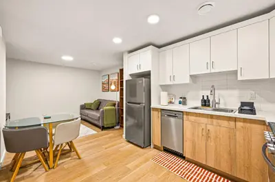 a kitchen with white cabinets and a table and a couch at Cozy 2BR BSMT Suite with Board Games and Netflix in Calgary
