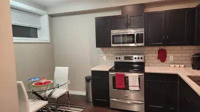 a kitchen with a stove and microwave and a table at Oasis at Heritage in Fort McMurray