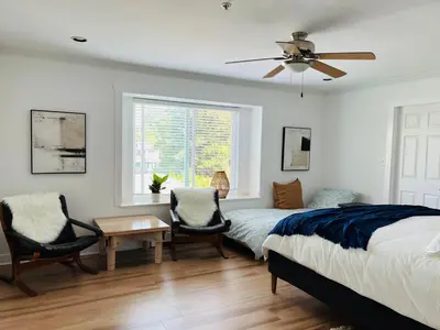 a bedroom with a bed and two chairs and a window at Luxury New 5-bedroom 4- bathroom Single House in Surrey