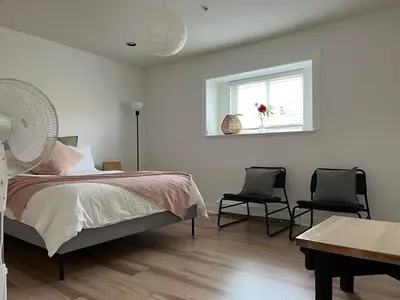 a bedroom with a bed and two chairs and a window at Luxury New 5-bedroom 4- bathroom Single House in Surrey