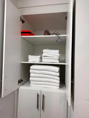 a white closet with white towels on shelves at Homey Basement Suite by Gaudi in Calgary