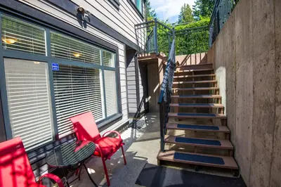 a balcony with a red chair and stairs next to a building at Beach Breeze White Rock in White Rock
