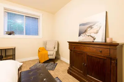a living room with a dresser and a chair at Beach Breeze White Rock in White Rock